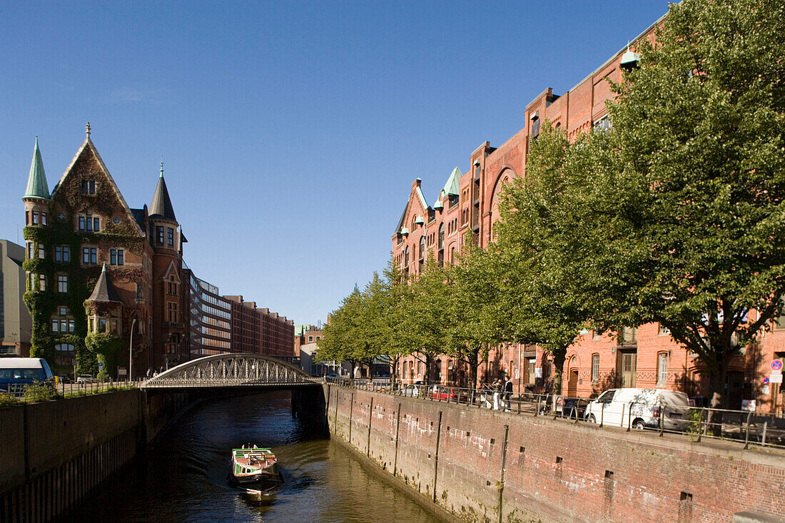 Barge passing brick-lined buildings of the Speicherstadt, Barge passing brick-lined buildings of the Speicherstadt at harbour, Hamburg, Germany