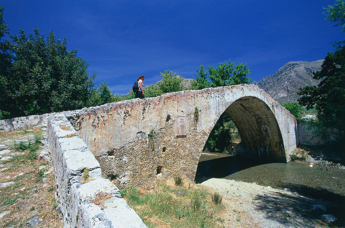 Hiker on venetian bridge near Kato, Monte Preveli, Crete, Greece