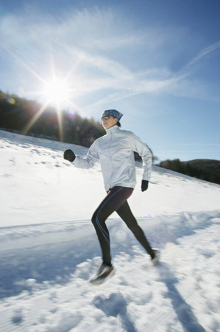 Junge Frau joggt durch Winterlandschaft