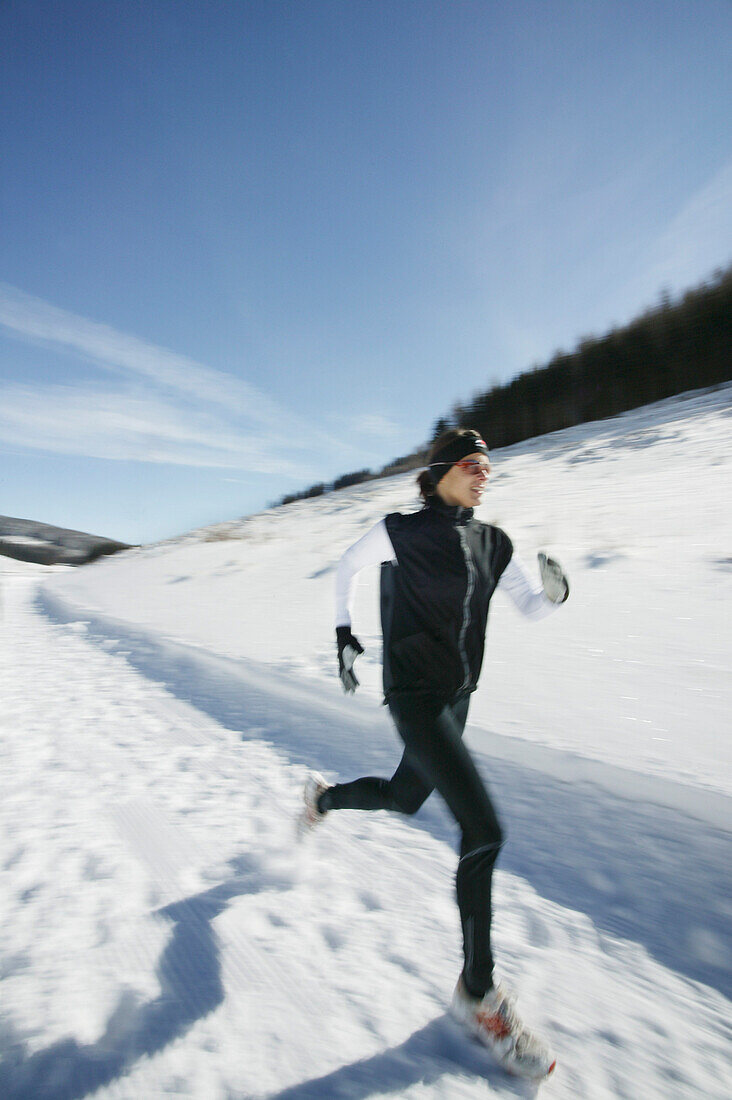 Junge Frau läuft durch Winterlandschaft