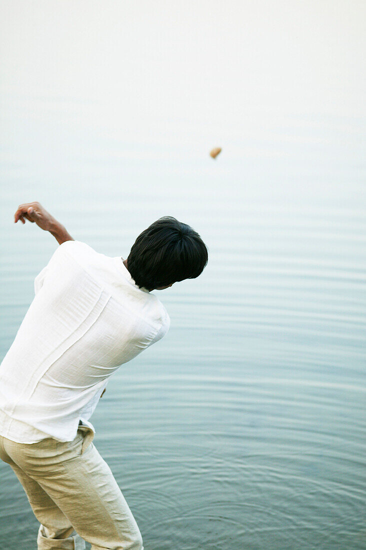 Man throwing stone into lake