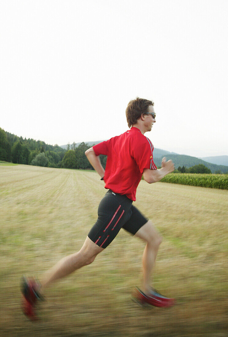 Young man jogging on country road