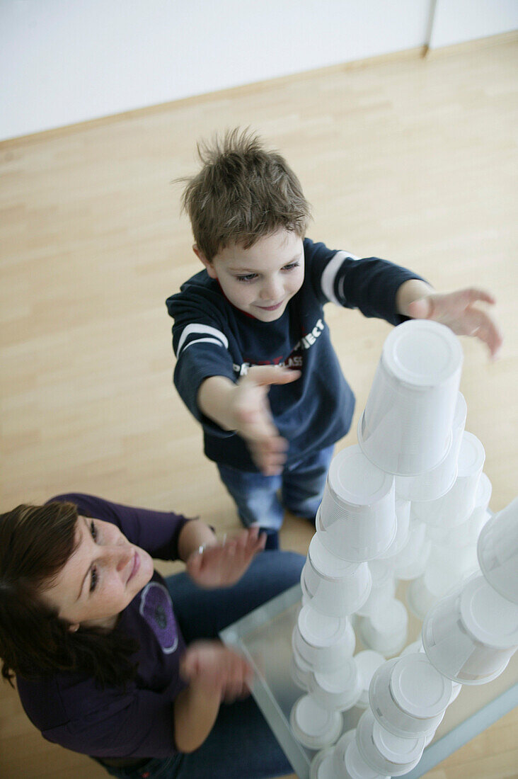 Junge baut einen Turm aus Plastikbechern