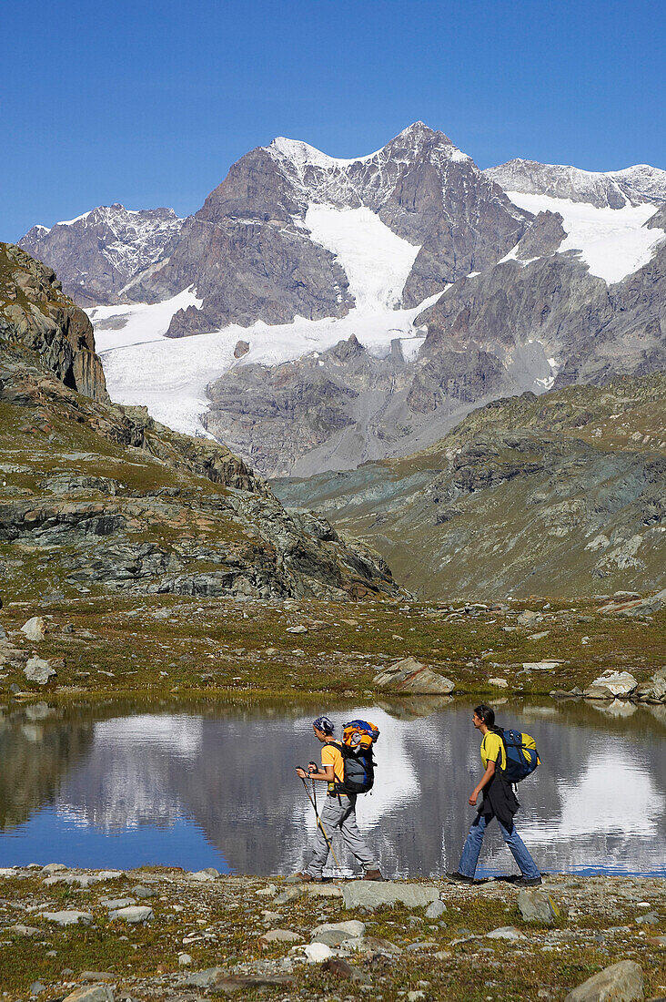 Zwei junge Frauen wandern vor einem Bergsee. Pass Cancian. Veltlin, Puschlav, Grenze, Italien, Schweiz Alpen