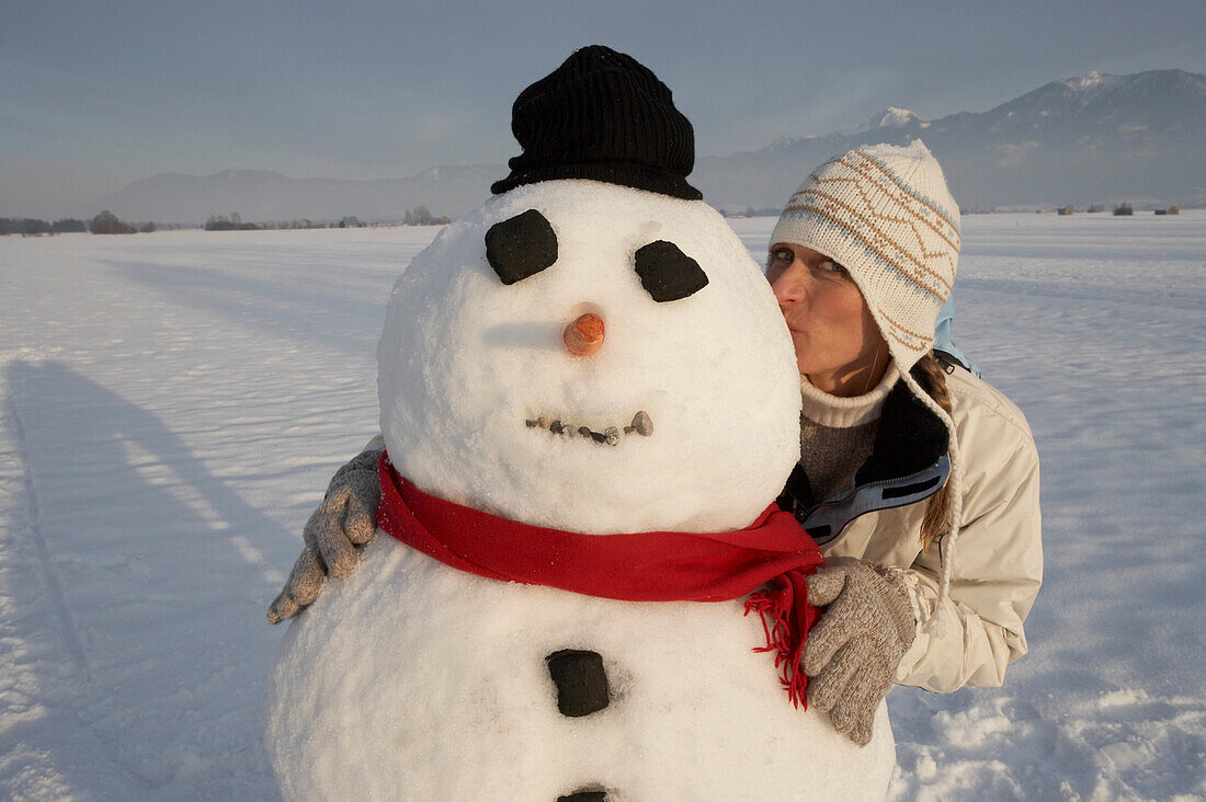 Woman kissing snowman