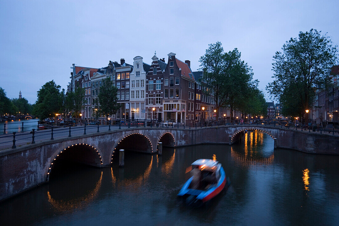Boat, Keizersgracht, Leidsegracht, A speedboat passing illuminated stone bridge in the evening, Keizersgracht and Leidsegracht, Amsterdam, Holland, Netherlands