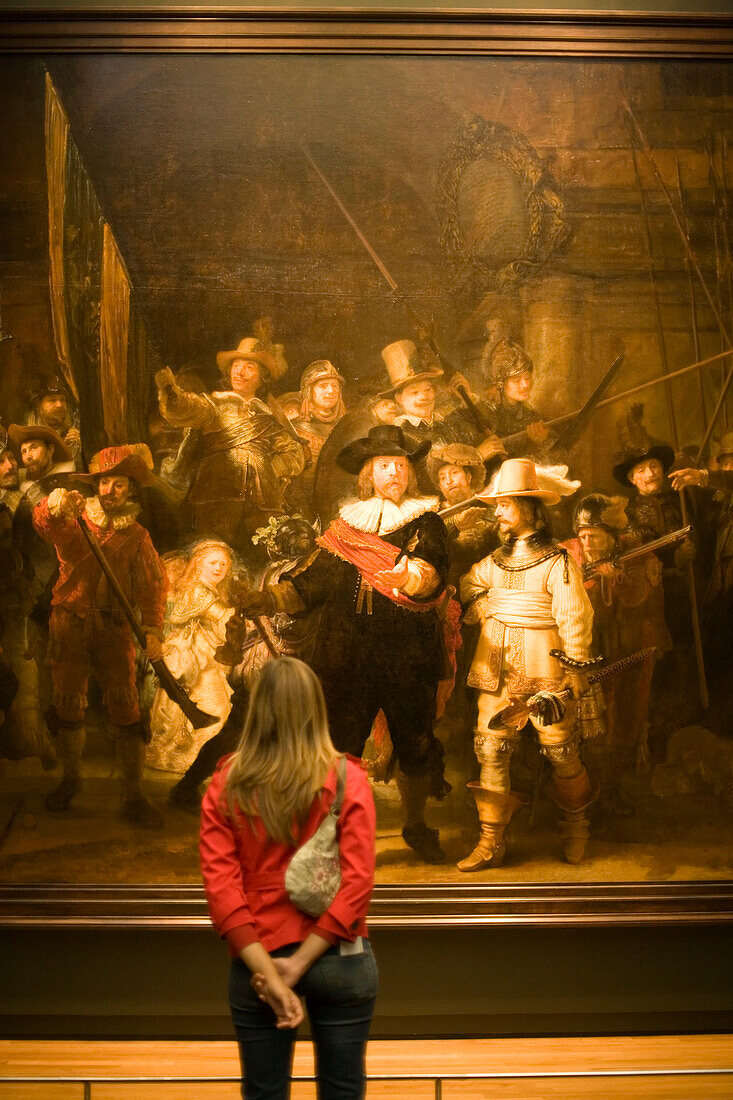 Visitor looking at painting The Night Watch by Rembrandt, Rijksmuseum, Amsterdam, The Netherlands