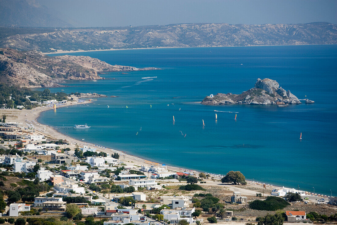 View over beach and bay of Kefalos with surfer to Kastri island with chapel St. Nicholas, Kefalos, Kos, Greece