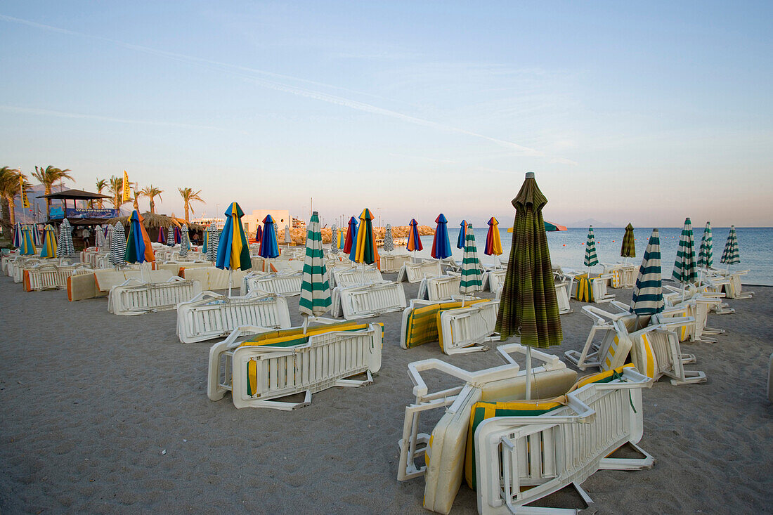 Deserted beach with closed sunshades and deck-chairs in the morning, Kardamena, Kos, Greece