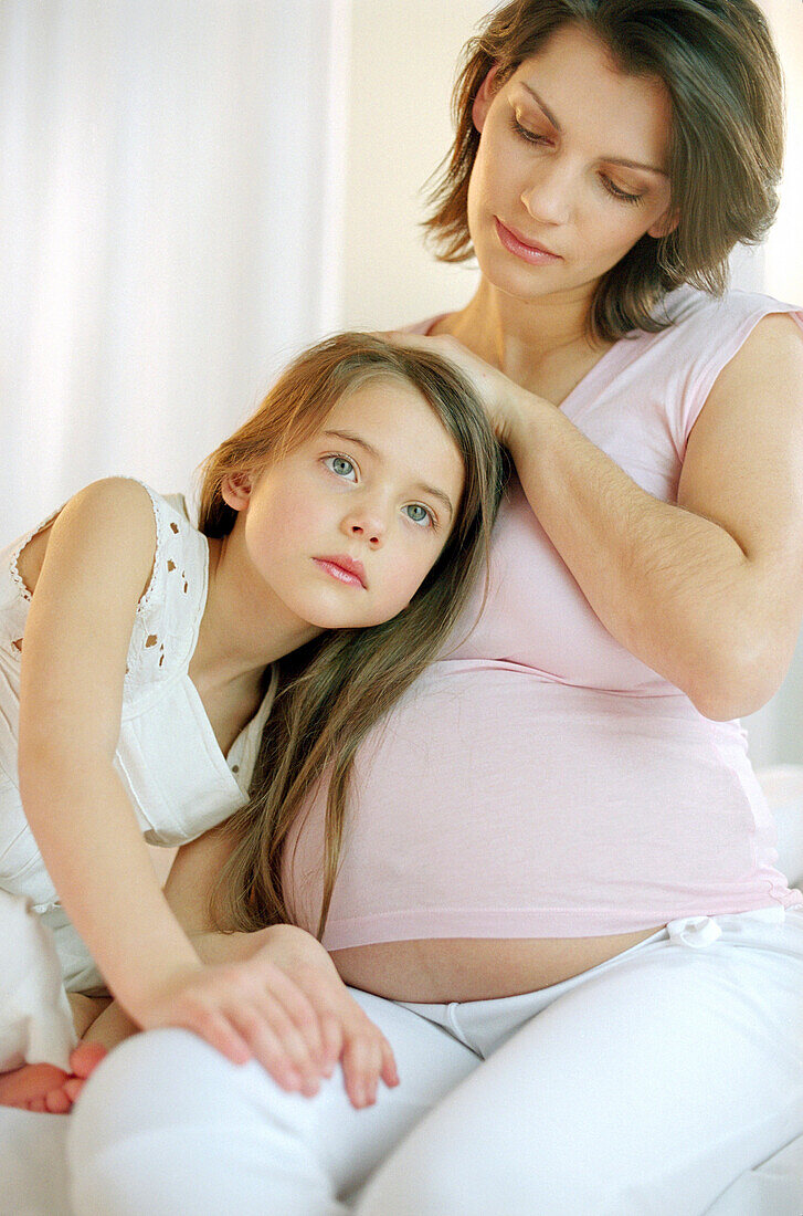 Mädchen hört am Bauch ihrer schwangeren Mutter