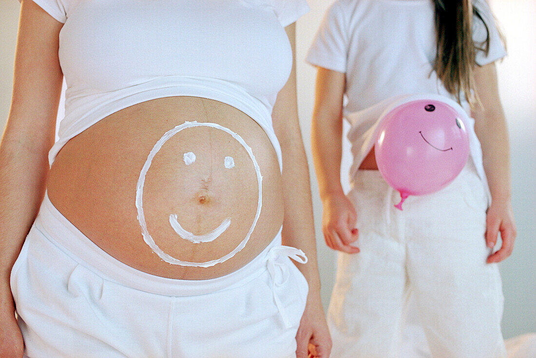 Pregnant woman with happy face on stomach