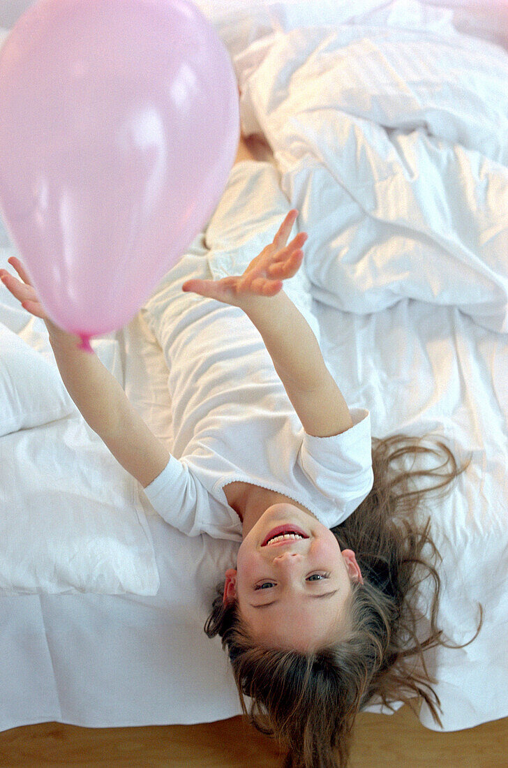 Mädchen spielt mit rosa Luftballon