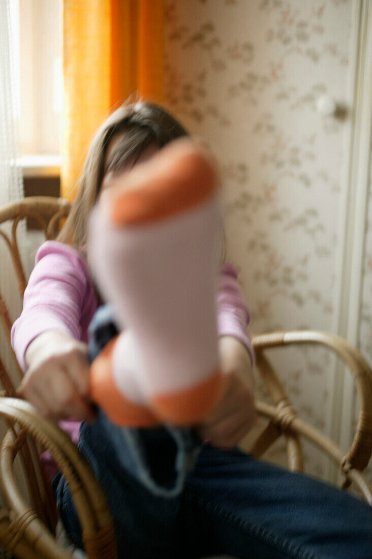 Girl sitting in wickery chair,showing her foot