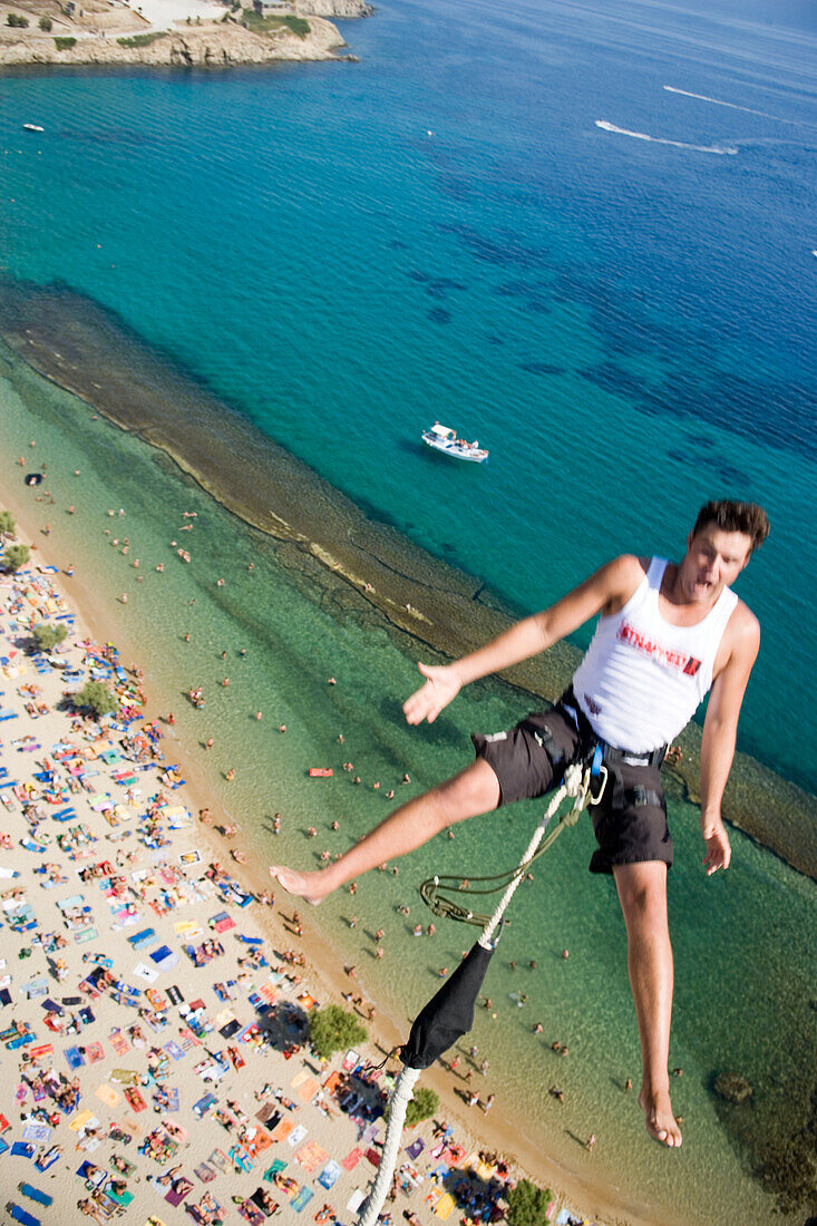 Young man bungee jumping over Paradise Beach, Mykonos, Greece