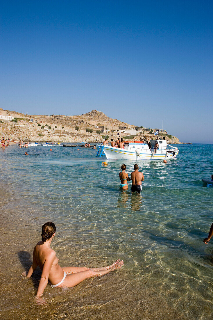 View over peopled Paradise Beach, Boat arriving, taking tourits to the beach,  Mykonos, Greece