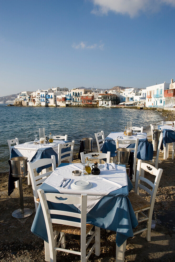 View along street with restaurants and bars, windmills in background, Little Venice, Mykonos-Town, Mykonos, Greece