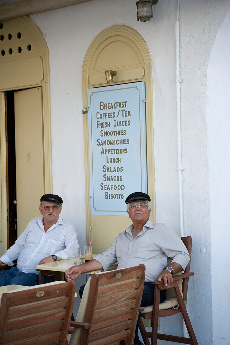 Two local men sitting in front of a tavern and having something to drink, Mykonos-Town, Mykonos, Greece