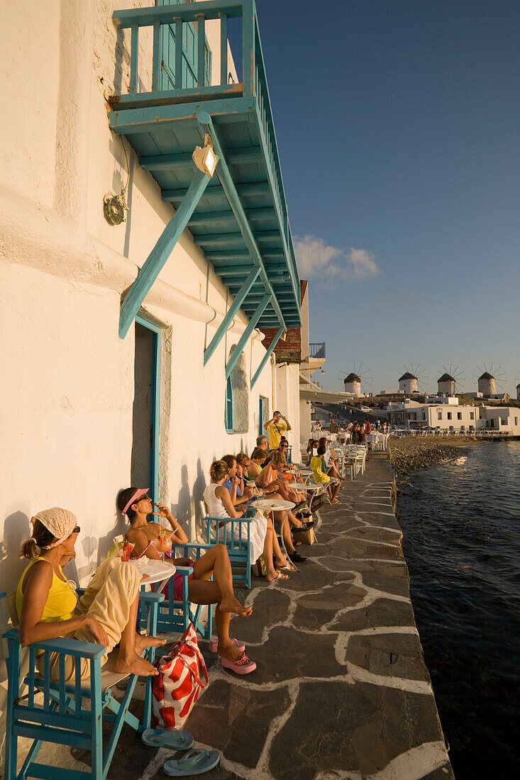 People sitting in Caprice Bar directly at sea, windmills in background, Little Venice, Mykonos-Town, Mykonos, Greece