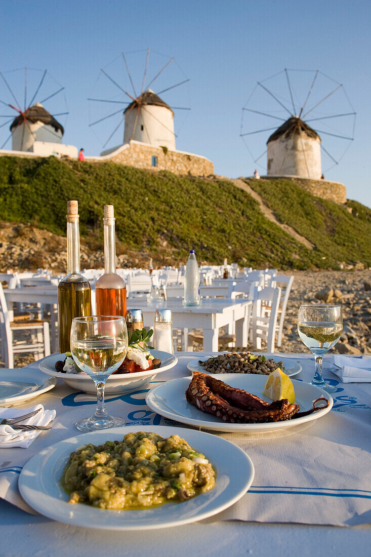Different greek starters served in the Sea Satin Market Restaurant, windmills in background, Mykonos-Town, Mykonos, Greece