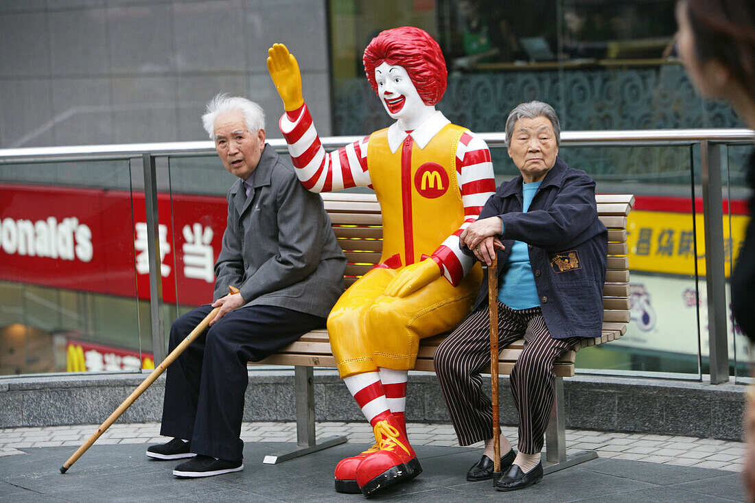 Ronald McDonald figure,pensioners rest on a bench, Seinoren auf der Bank, Fastfood