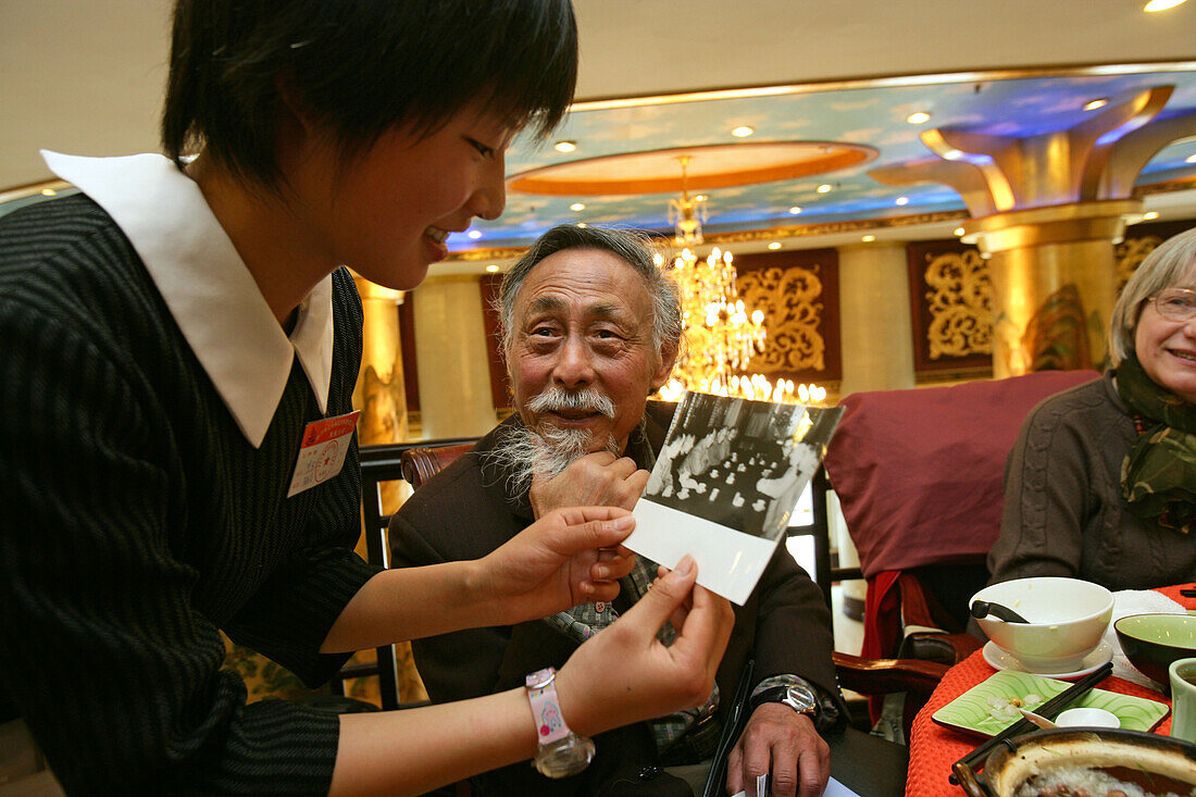Übersetzer Zhou Chun,translator Prof. Zhou Chun, shows a waitress a photo of him with Chou En Lai, war einst Dolmetscher von Tschou En Lai und Mao Tse Tung , Großer Vorsitzender, dann politisch verfolgt, "Rechtsabweichler", Gefängnis, kommunstischer Terro