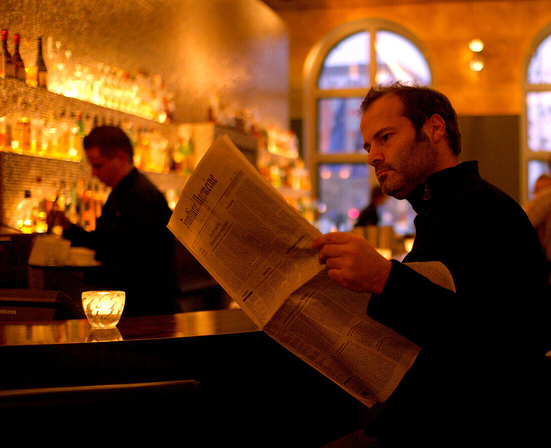 Man reading newspaper at bar, Hotel Sofitel, Munich, Bavaria, Germany
