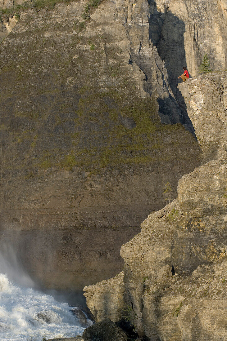 Man sitting on a rock high above virginia falls, Mackenzie Mountains, Northwest-Territories, Canada