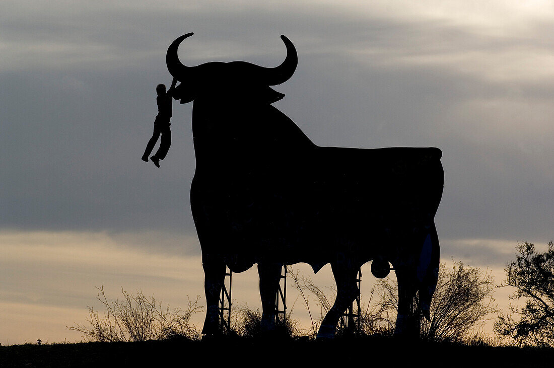 Mann klettert auf einen Metall Stier, Mallorca, Spanien