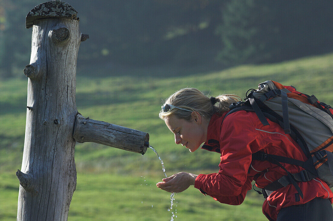 Junge Wandererin beim Wassertrinken auf einer Salzburger Alm, Salzburger Land, Österreich
