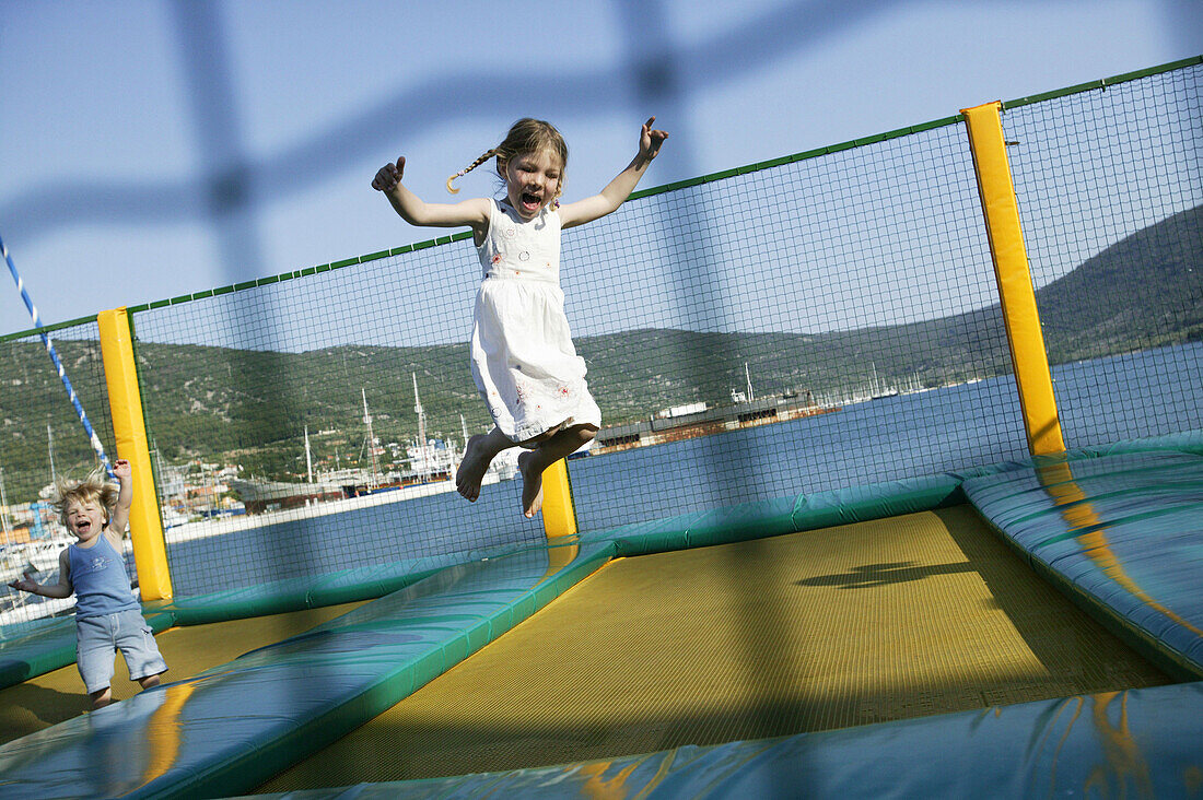 Girl jumping on trampoline, Harbour of Cres,  Cres Island, Croatia