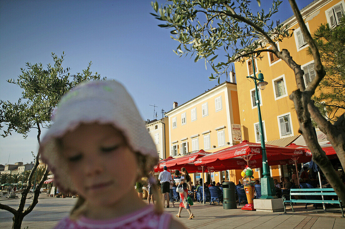 Girl with cafe and houses along the waterfront, Mali Losinj harbour, Cres Island, Croatia