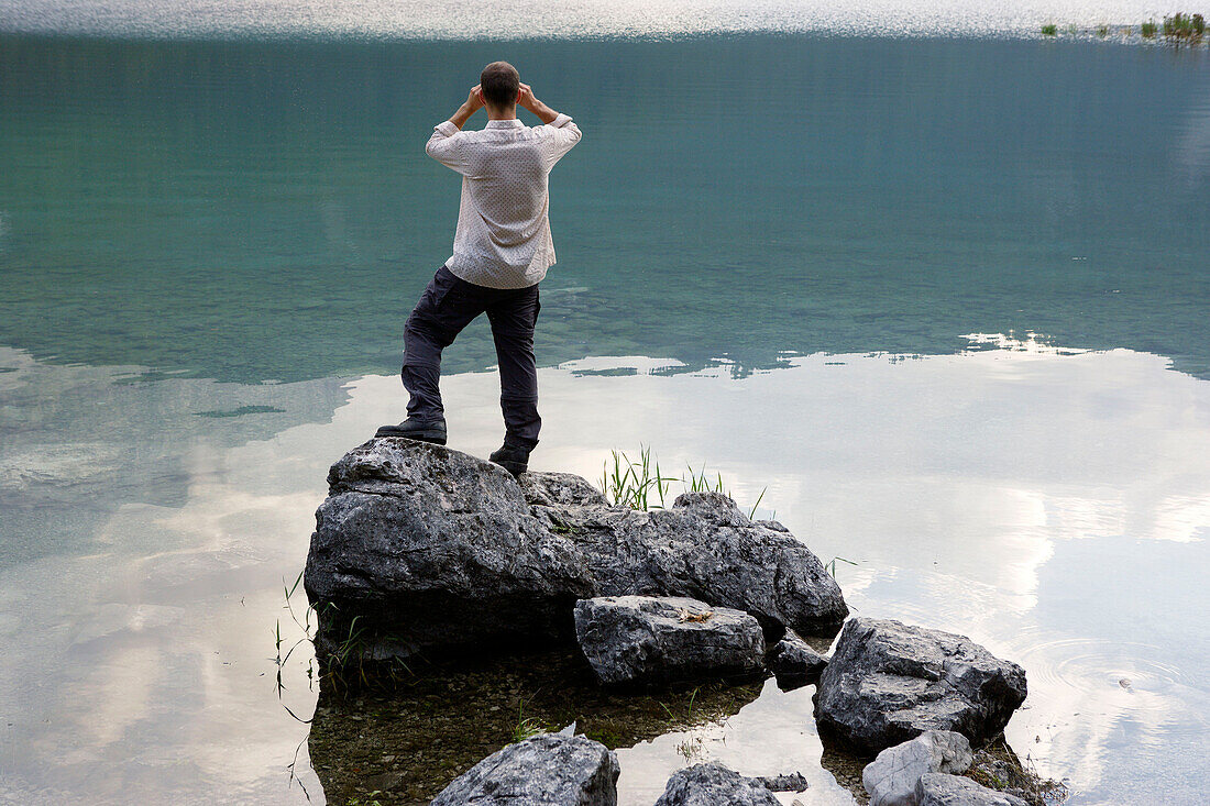 Man looking with binocular over Lake, Eibsee, Zugspitze in backround, Bavaria Germany