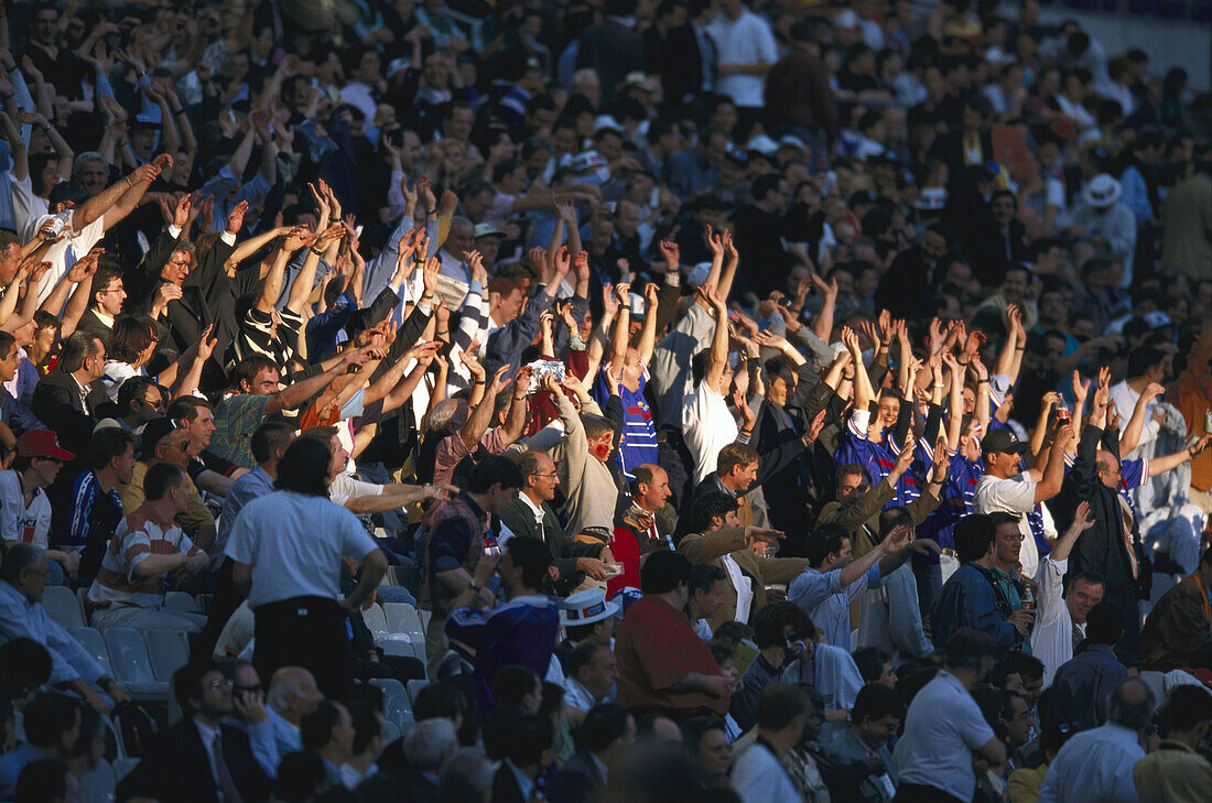 Fans at the football stadium stretching up their arms