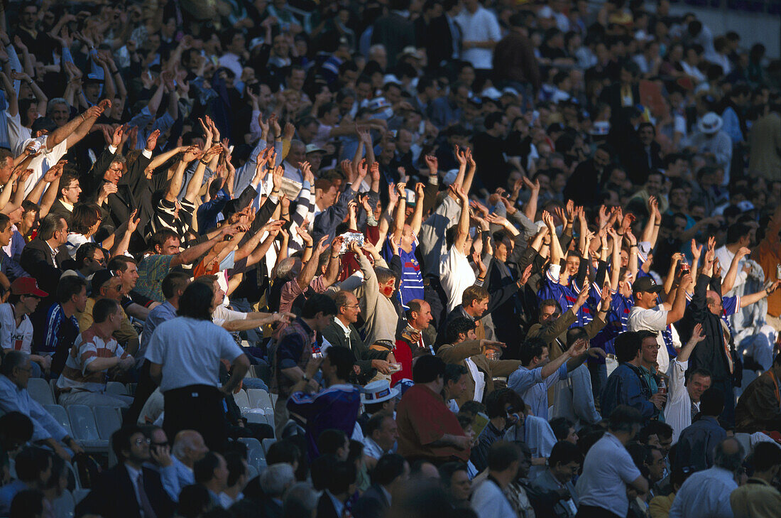Fans im Fußballstadion strecken ihre Arme hoch