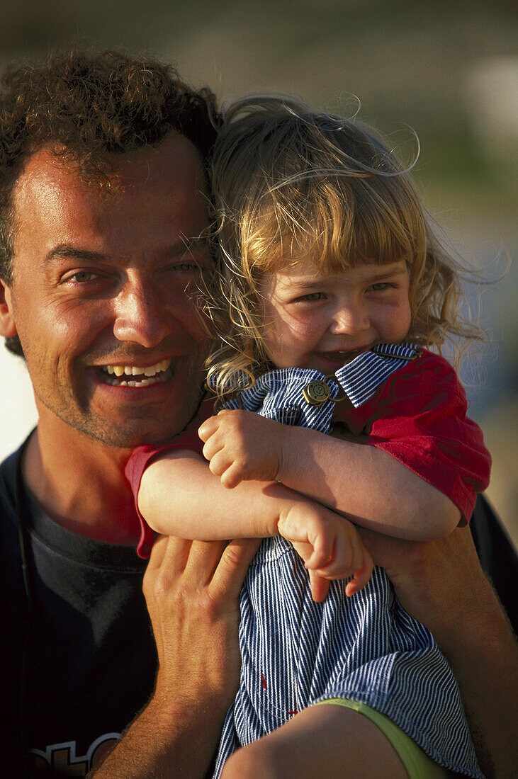 Father holding daughter, casual clothing