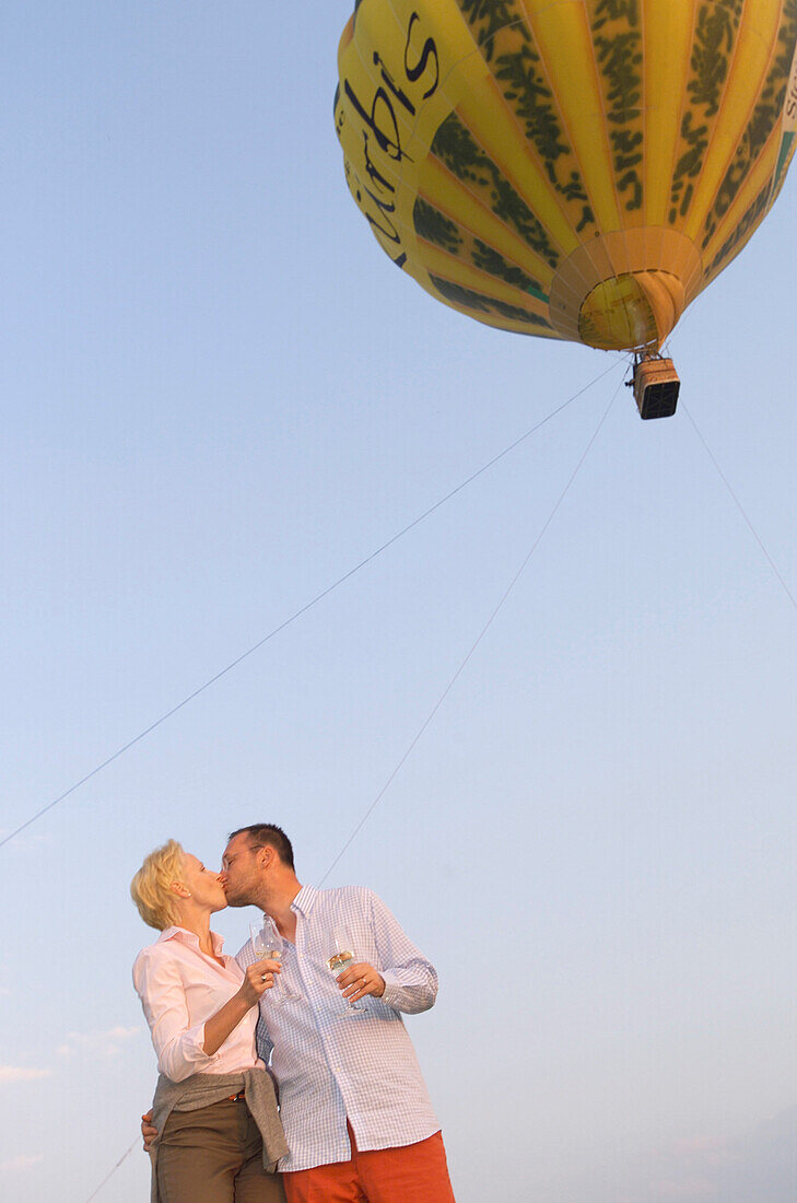 Couple kissing in front of hot air balloon