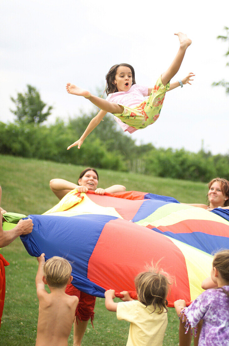 Playing children with a colored trampolin in the meadow