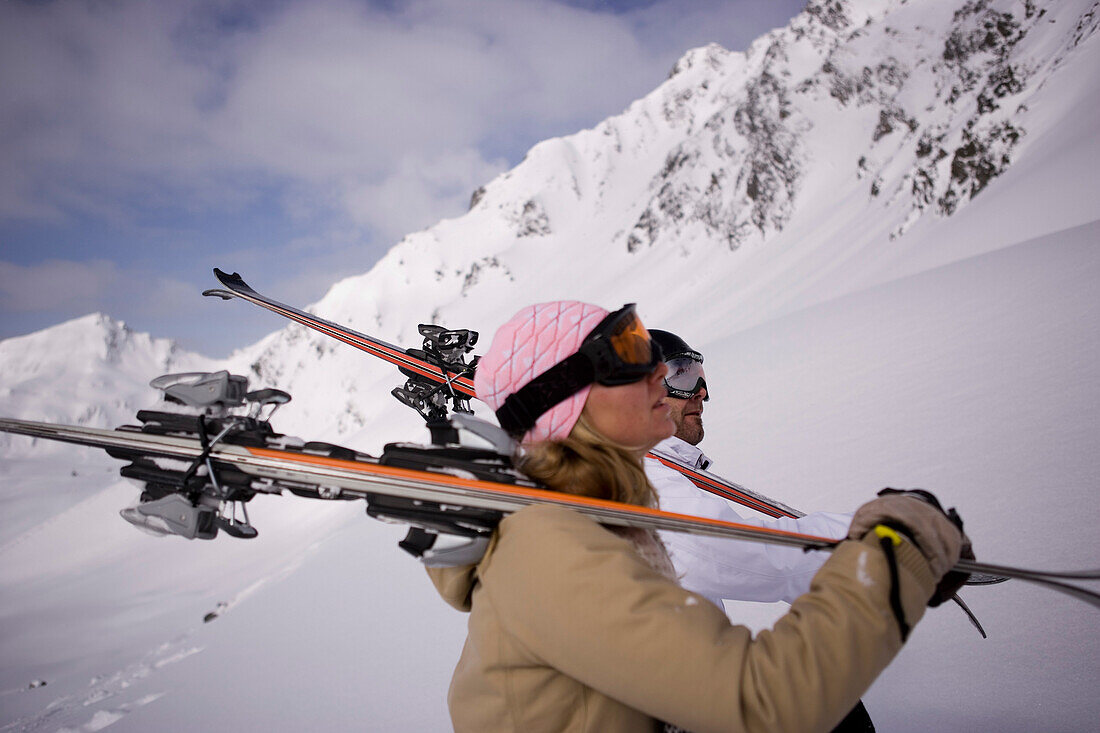 Young couple carrying skis on shoulders, Kuehtai, Tyrol, Austria