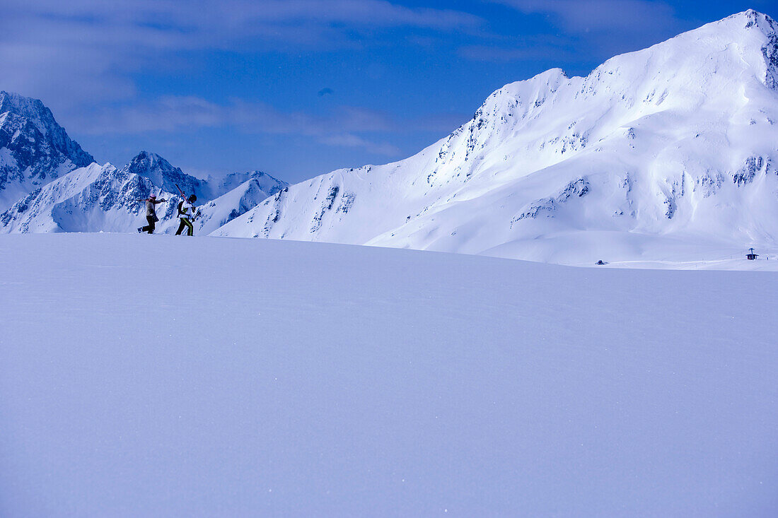 Zwei Skifahrer laufen auf schneebedecktem Berg, Kühtai, Tirol, Österreich