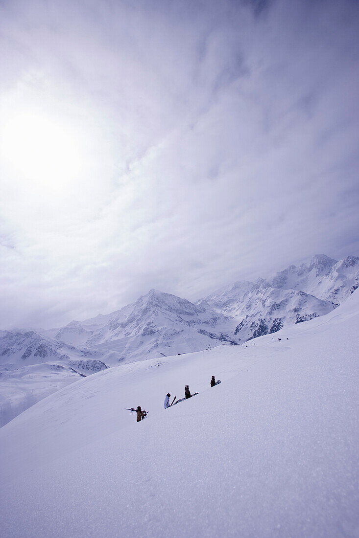 Snowboarder und Skifahrer laufen einen Berg hinauf, Kühtai, Tirol, Österreich