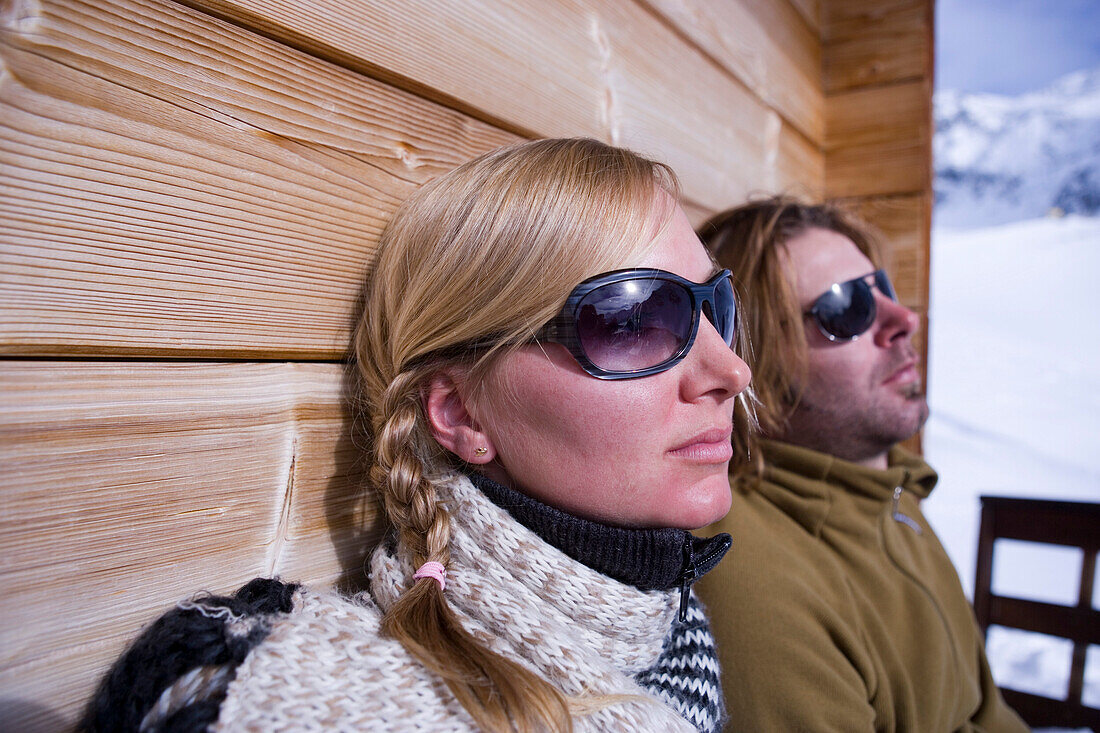 Couple sunbathing on terrace of ski lodge, Kuehtai, Tyrol, Austria