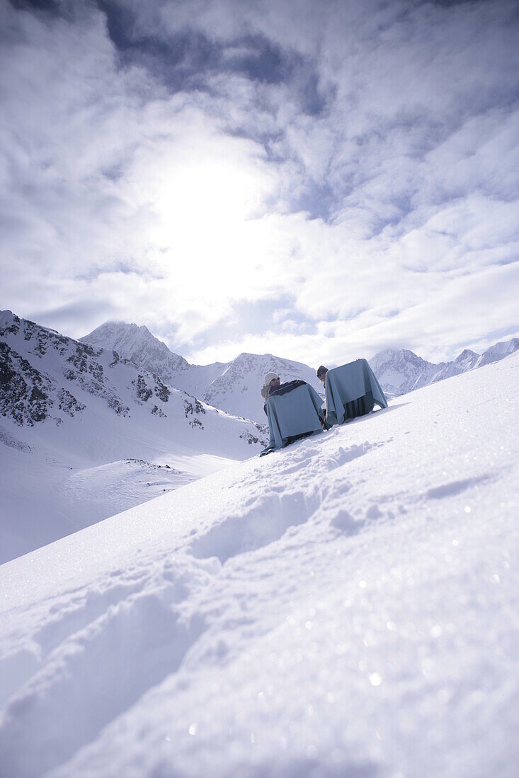Zwei Personen in Liegestühlen im Schnee, Kühtai, Tirol, Österreich