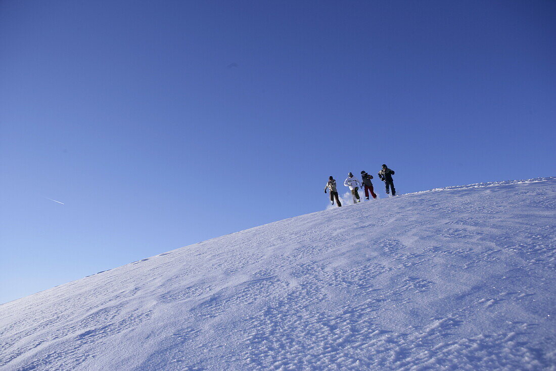 Group of young people running downhill snowcapped mountain, Kuehtai, Tyrol, Austria