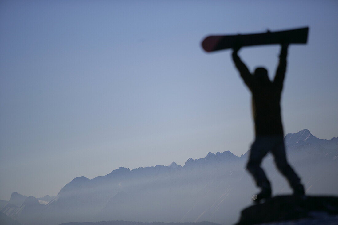 Person hebt Snowboard in die Höhe, Kühtai, Tirol, Österreich