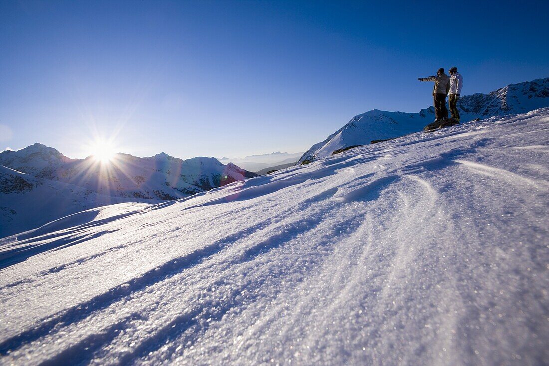 Two people on ski slope looking mountain panorama, Kuehtai, Tyrol, Austria