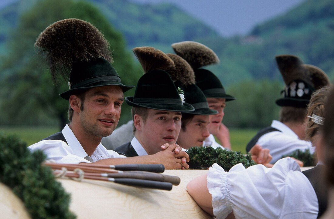 Four young men wearing hats with tufts of chamois hair at a maypole festival in Flintsbach, Upper Bavaria, Germany