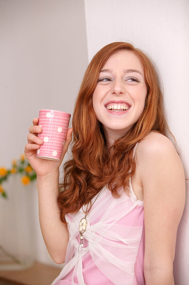 Junge Frau lächelt mit Tasse in der Hand