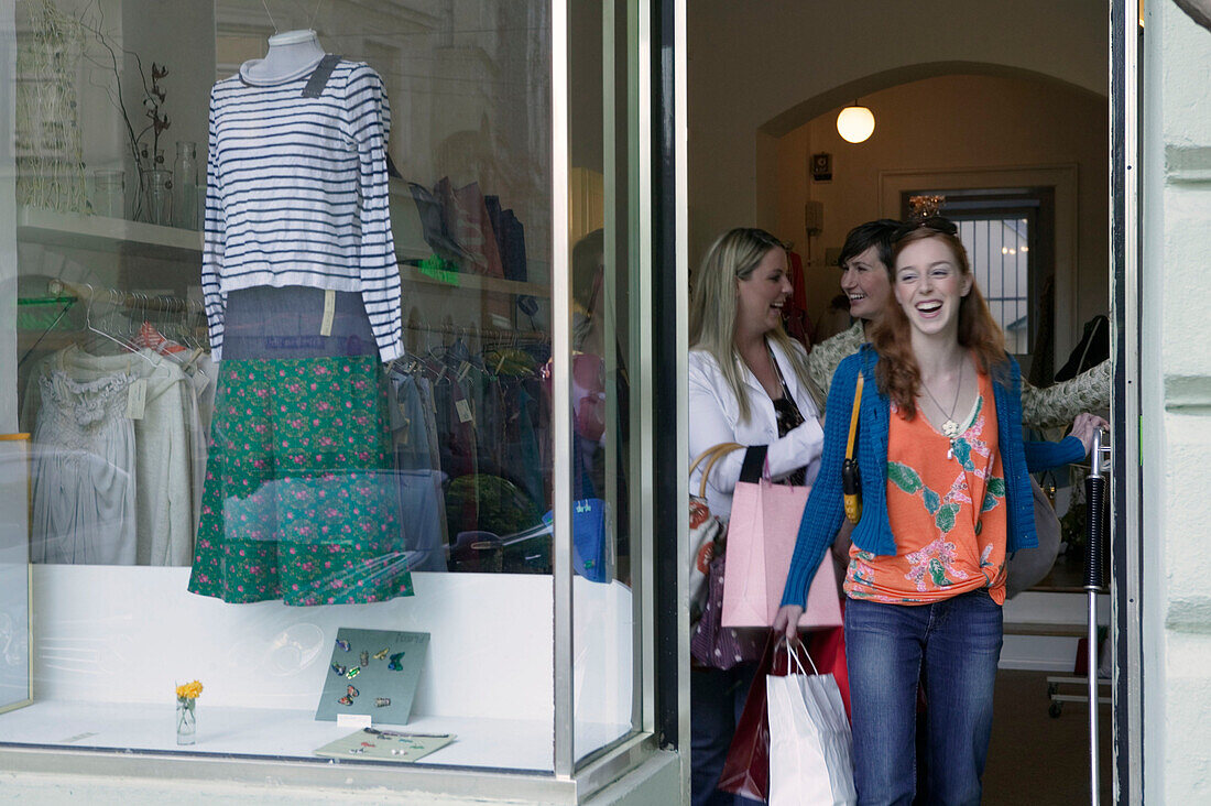 Junge Frauen beim Einkaufen treten aus einem Laden