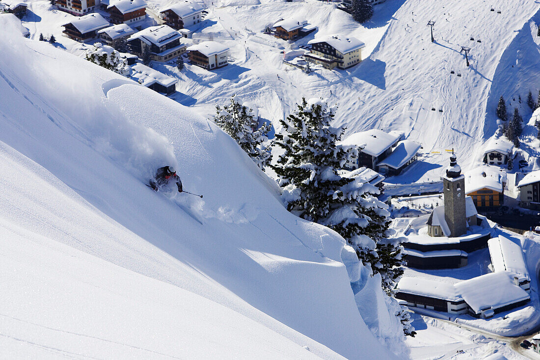 Ein Skifahrer, ein Freerider fährt oberhalb der Kirche von Lech. Der Schnee bricht, es löst sich eine kleine Schneebrett Lawine. Lech, Zürs, Arlberg, Österreich, Alpen, Europa, MR