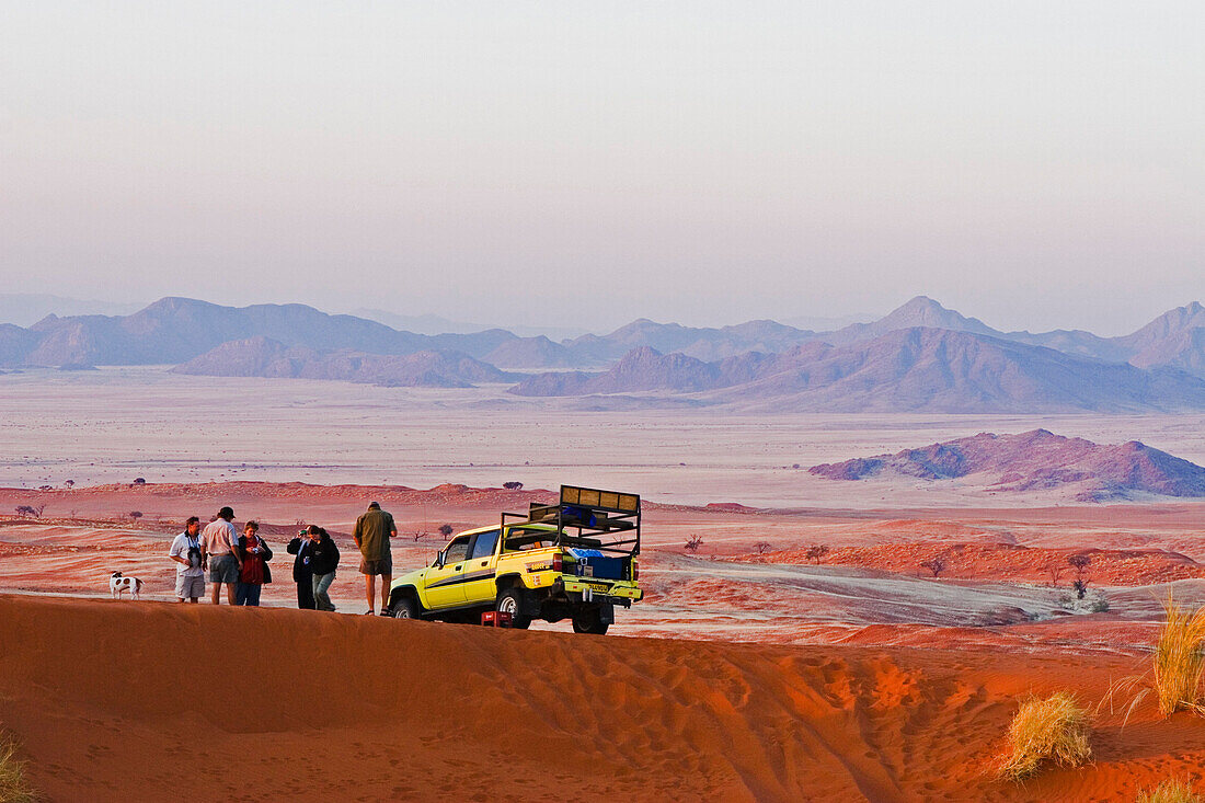 A group of people and car in the middle of the desert, just before sunset. Gondwana Namib Desert park. Namib Desert. Southern Nambia, Africa.